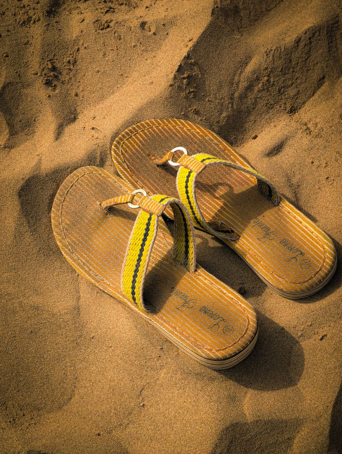 Pair of sandals resting on sunlit sandy beach, capturing a summer vibe.